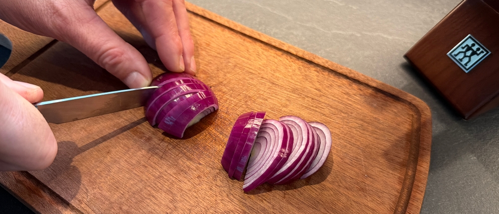 Mit einem kleinen Messer aus dem Messerset Zwilling 1002451 wird eine Zwiebel geschnitten.
