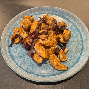 Fertig angebratene Zwiebeln und Fleisch auf einem blauen Teller