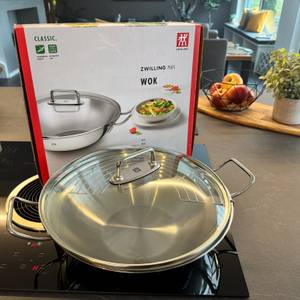Karton und Zwilling-Plus-Wok mit Deckel auf dem Kochfeld