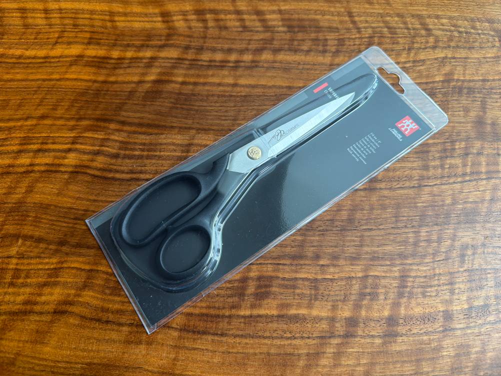 Die Zwilling-Schneiderschere liegt in ihrer Verpackung auf einem Tisch