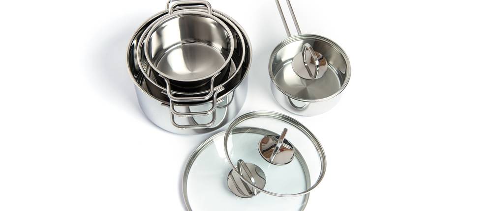 Zwilling-Topfset-Test: Vor weißem Hintergrund befinden sich in einander gestellte Edelstahltöpfe, daneben ein Stieltopf und zwei Topfdeckel aus Glas.