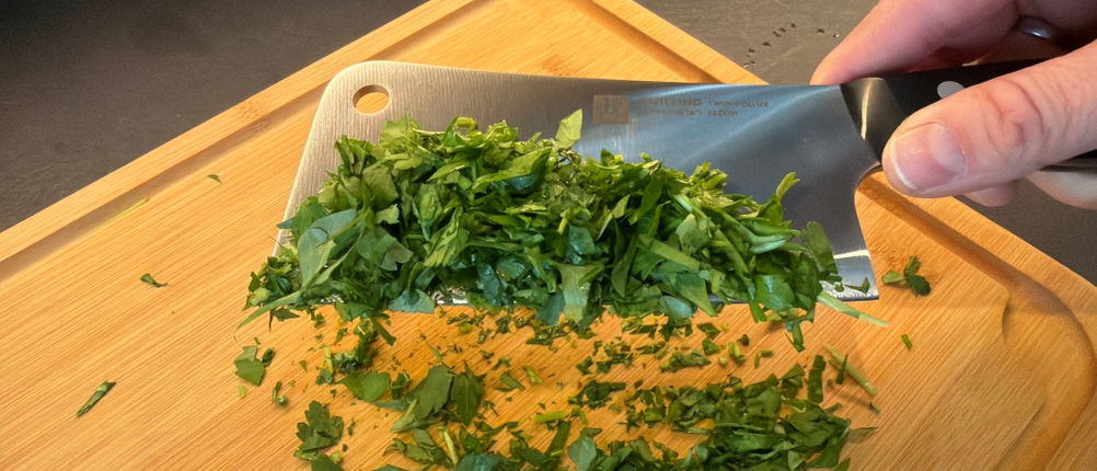 Zerkleinerte Petersilie hängt am Zwilling-Twin-Pollux-Hackmesser 30795150