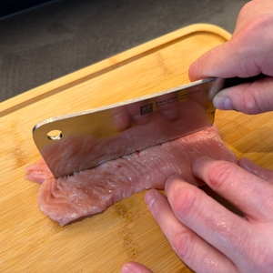 Ein Stück Fleisch wird mit dem Zwilling-Twin-Pollux-Hackmesser 30795150 geschnitten