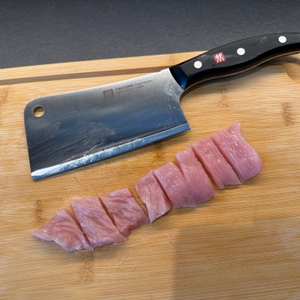 Fleischstücke liegen neben dem Zwilling-Twin-Pollux-Hackmesser 30795150