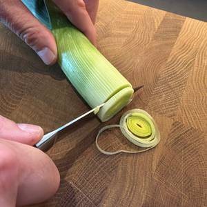 Eine Hand schneidet mit dem Zwilling-Vier-Sterne-Spick- und Garniermesser einen Porree