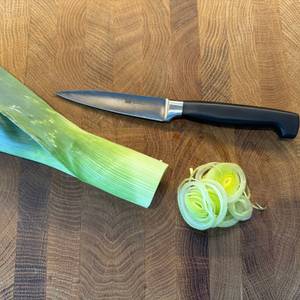 Ein geschnittener Porree liegt neben dem Zwilling-Vier-Sterne-Spick- und Garniermesser