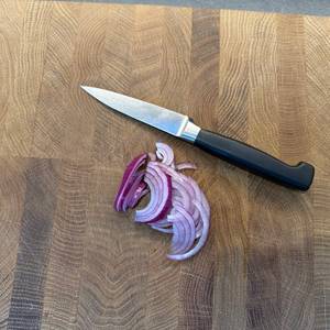 Eine geschnittene Zwiebel liegt neben dem Zwilling-Vier-Sterne-Spick- und Garniermesser