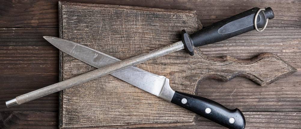 Zwilling-Wetzstahl-Test: Ein Messer und ein Wetzstahl liegen gekreuzt übereinander auf einem Holzbrett
