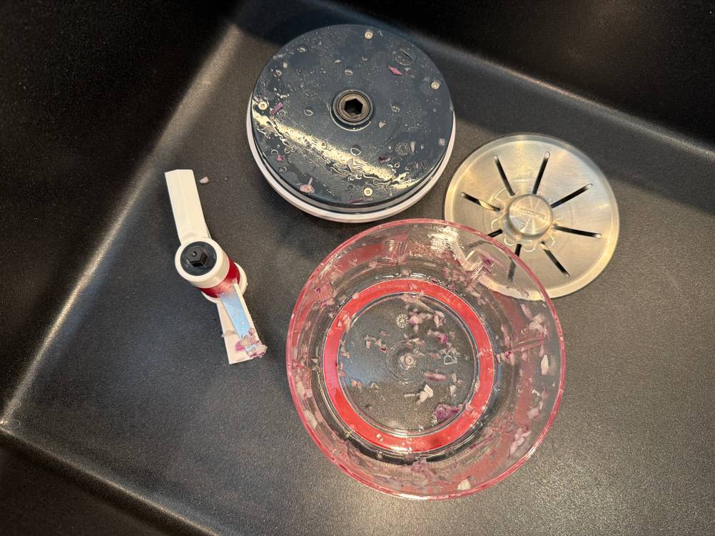 Der verschmutzte Behälter des Zyliss Easy Pull E910015 liegt in einem Spülbecken.