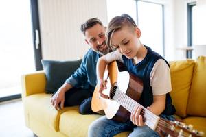vater mit sohn spielen gitarre
