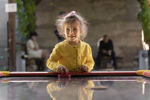 mädchen in gelber jacke spielt air hockey