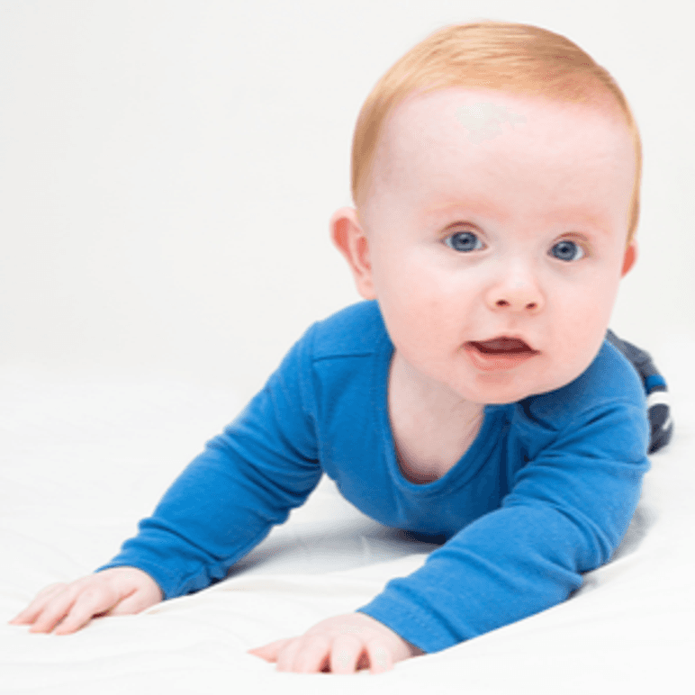 baby in blauem body auf matratze