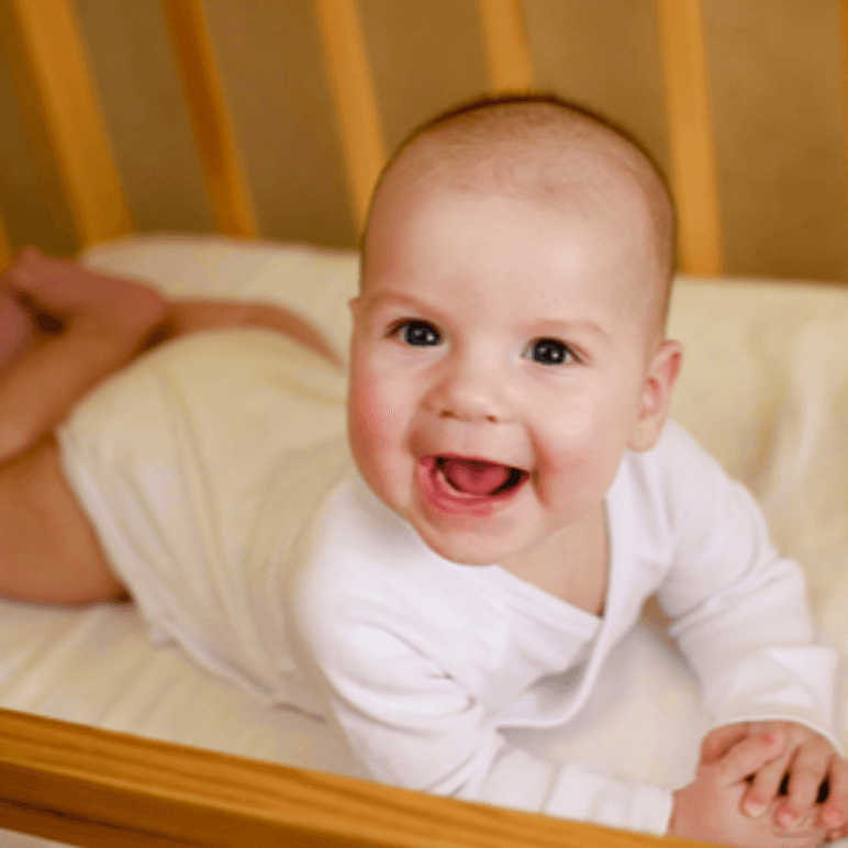 froehliches baby auf babymatratze