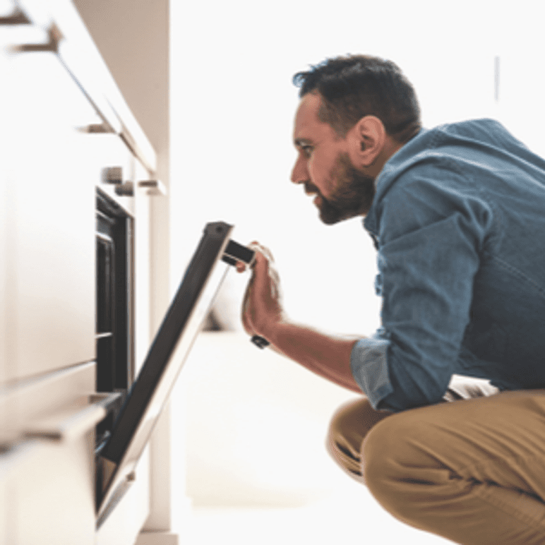 mann schaut in backofen
