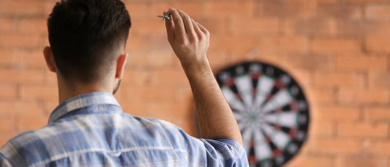 junger mann spielt dart