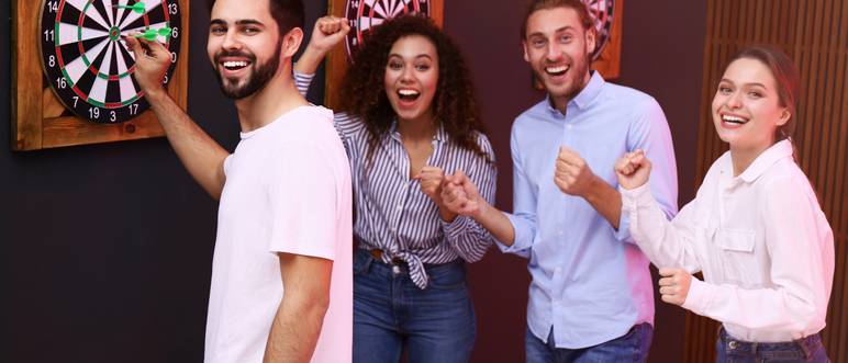 gruppe von freunden spielt dart in einer bar