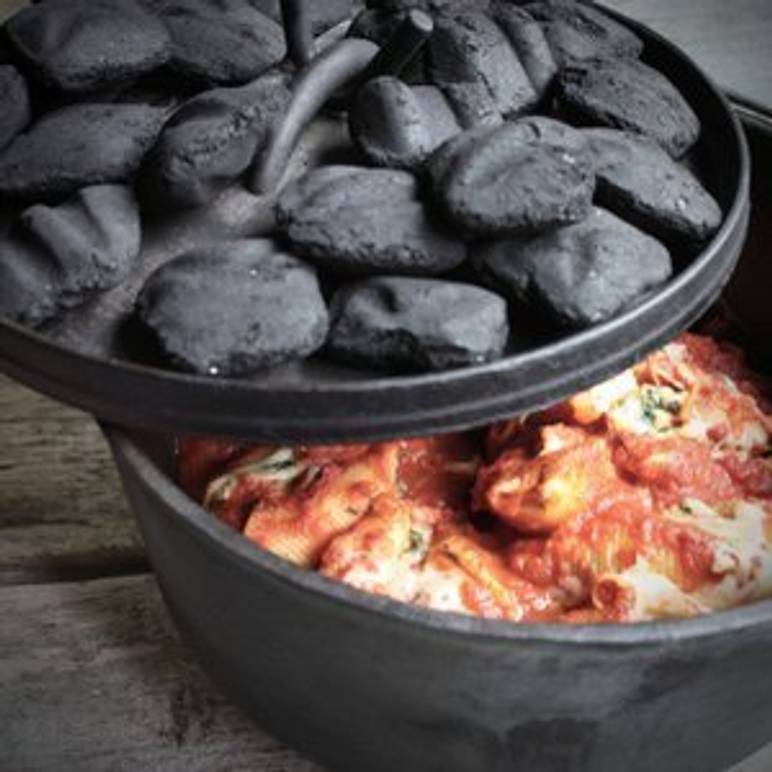 Dutch Oven, dessen Deckel mit Kohlen bedeckt ist