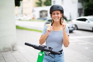 frau mit helm auf e-scooter