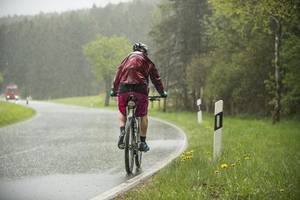 junger mann im regen auf dem fahrrad