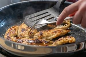 frau wendet fleisch mit gabel und pfannenwender