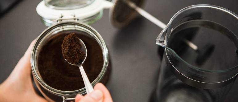 person füllt löffelweise kaffee in die frenchpress