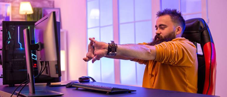 mann streckt sich vor monitor auf gaming-stuhl