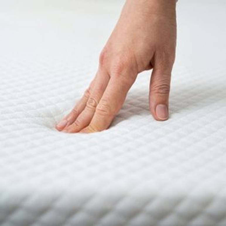hand drueckt auf matratzen-topper