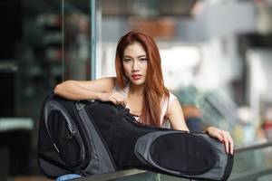 junge frau mit einer in eine gitarrentasche gehuellte gitarre