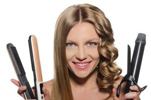 junge frau mit einem glaetteisen in der einen und einem lockenstab in der anderen hand