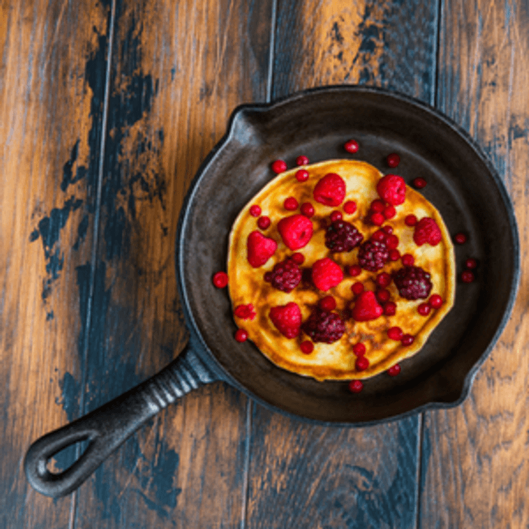 Gusseisenpfanne in der Pfannkuchen mit Beeren liegt