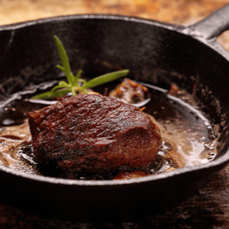 Gusseisenpfanne in der ein Steak brät