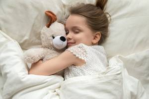 schlafendes maedchen mit einem kuscheltier im arm