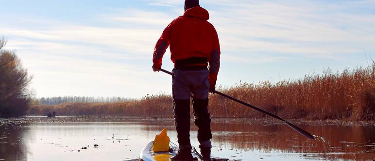 mann fährt sup-board im winter