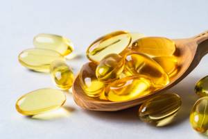 omega-3-kapseln auf holzloeffel