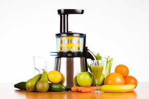 slow-juicer mit obst, gemuese und einem glas frisch gepresstem saft