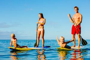 familie mit aufblasbaren sup-boards auf dem meer