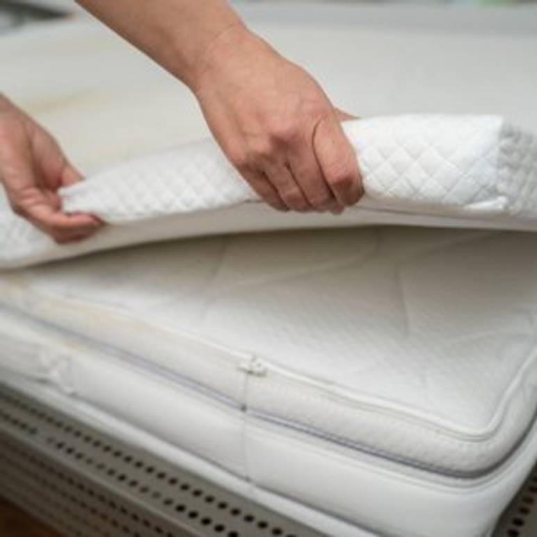 Frau, die 140x200 Zentimeter-Topper auf Matratzen legt