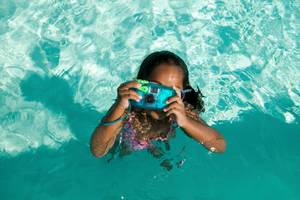kind mit unterwasser-einwegkamera im pool