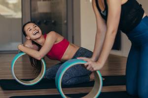 zwei lachende frauen beim workout mit yoga wheel